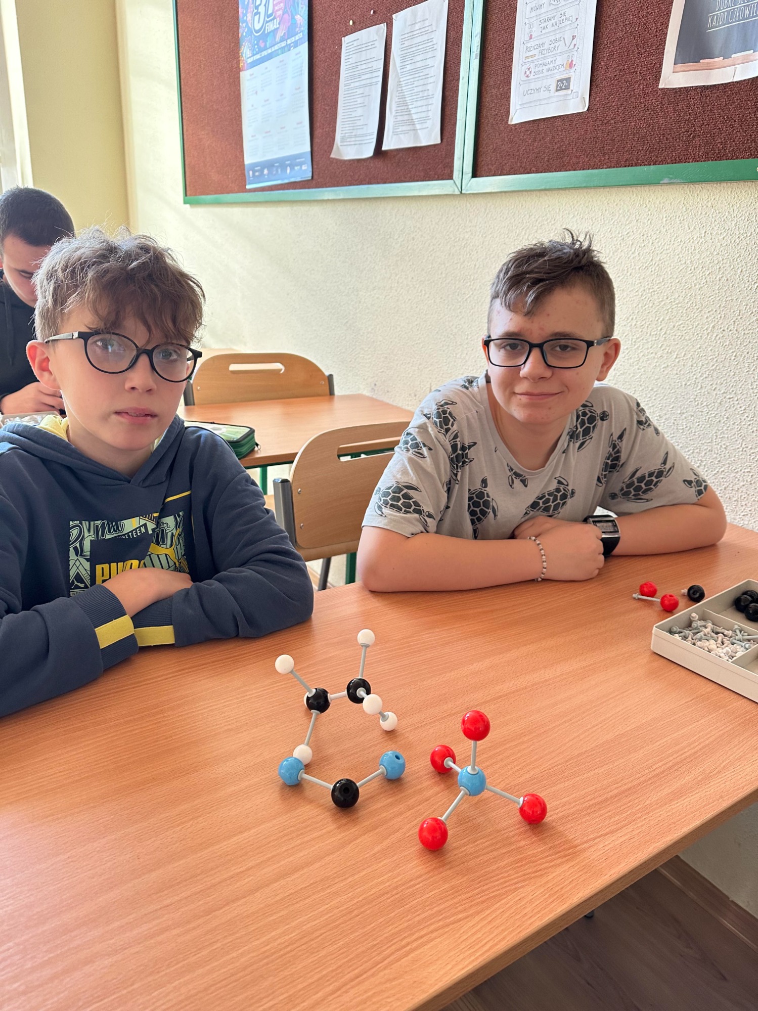 Chłopcy w klasie tworzą cząsteczki różnych pierwiastków i związków.