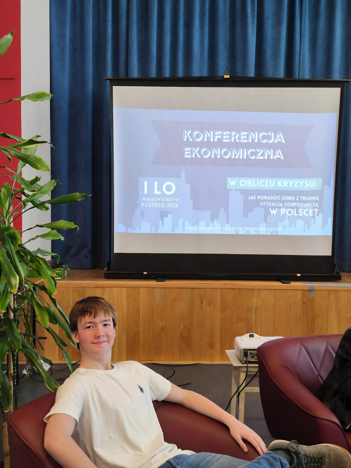 uczeń Bytnarówki siedzący przed ekranem z napisem konferencja ekonomiczna W obliczu kryzysu - Jak poradzić sobie z trudną sytuacją gospodarczą w Polsce