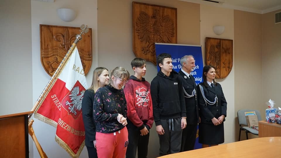 Nagrodzeni uczniowie pozują do zdjęcia z przedstawicielami straży pożarnej i starostą powiatu strzelecko - drezdeneckiego.