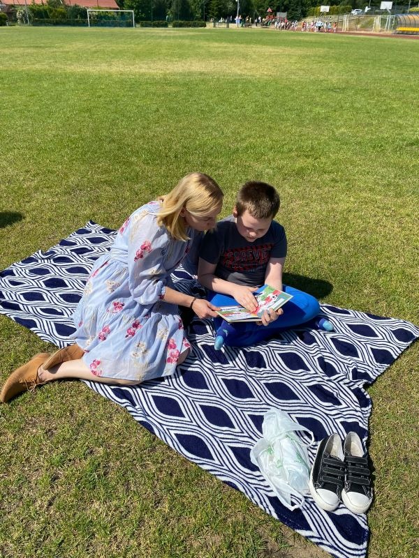 Kobieta i chłopiec siedzą na kocu piknikowym