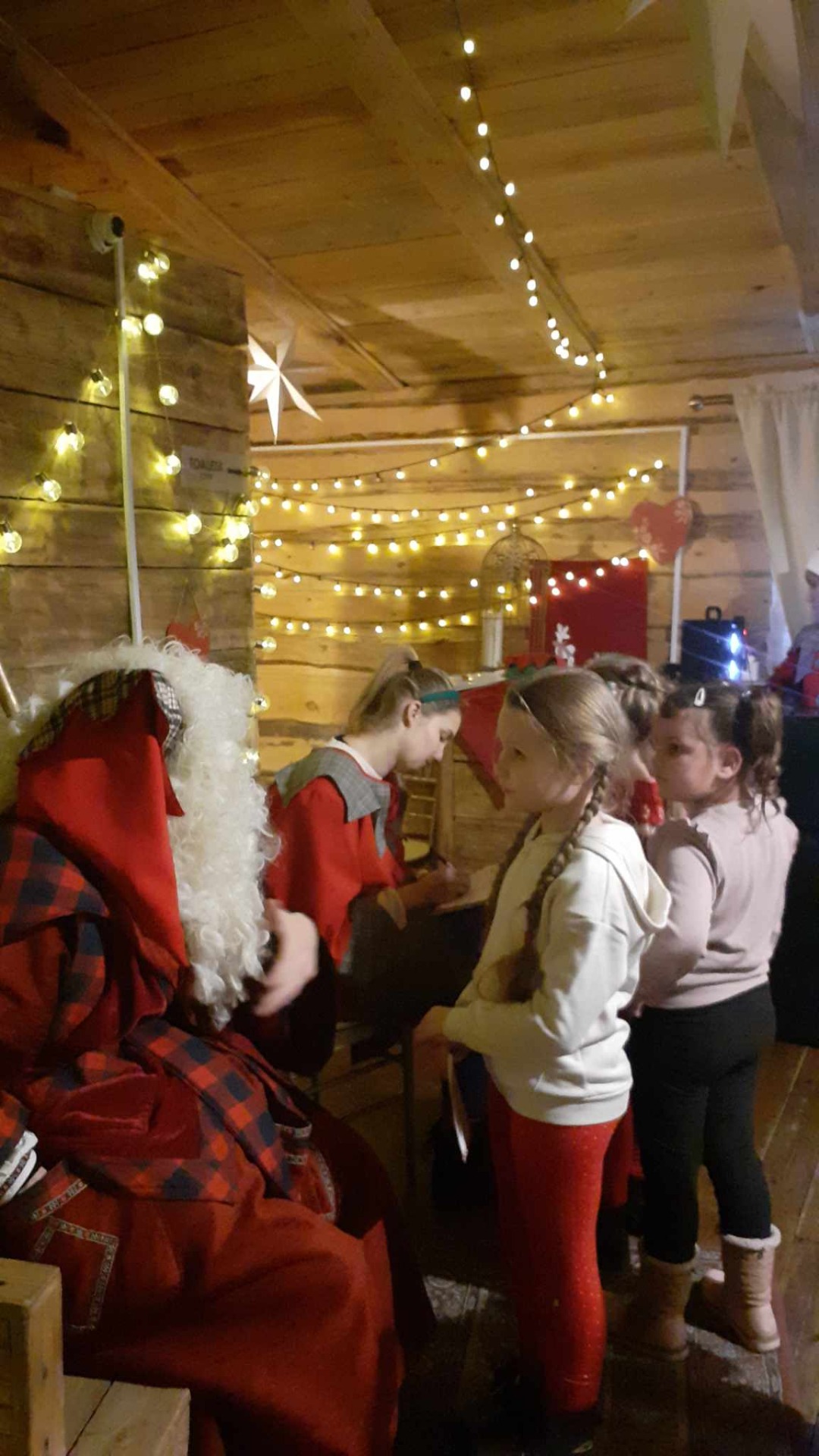 Grupa uczniów rozmawia ze Świętym Mikołajem i jego elfami.