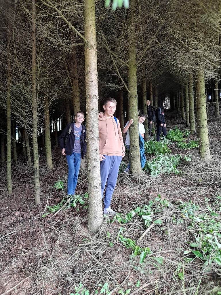 Pięcioro uczniów klasy 8b na spacerze w lesie.
