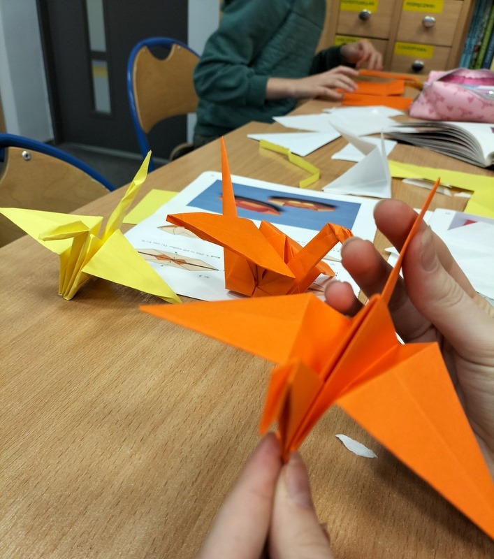 uczniowie składają żurawie z kolorowego papieru