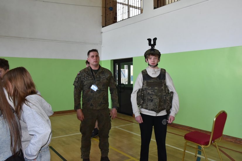 Żołnierze pokazują uczniom elementy wyposażenia wojskowego i wyjaśniają zasady jego wykorzystania