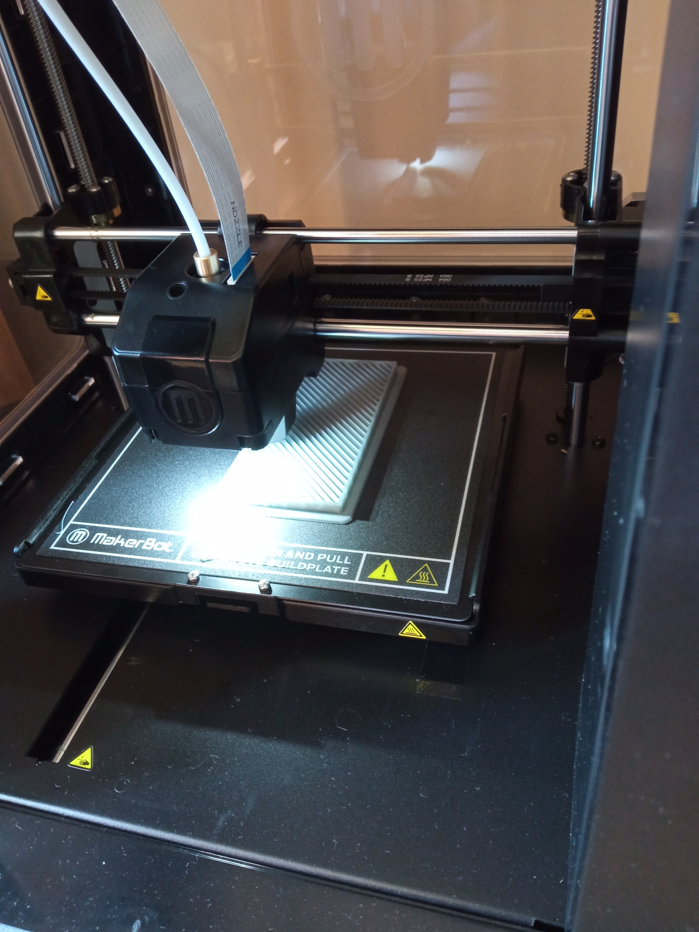 Widok drukarki, która wykonuje wydruk za pomocą głowicy na specjalnej platformie (zdjęcie w ze środka drukarki).