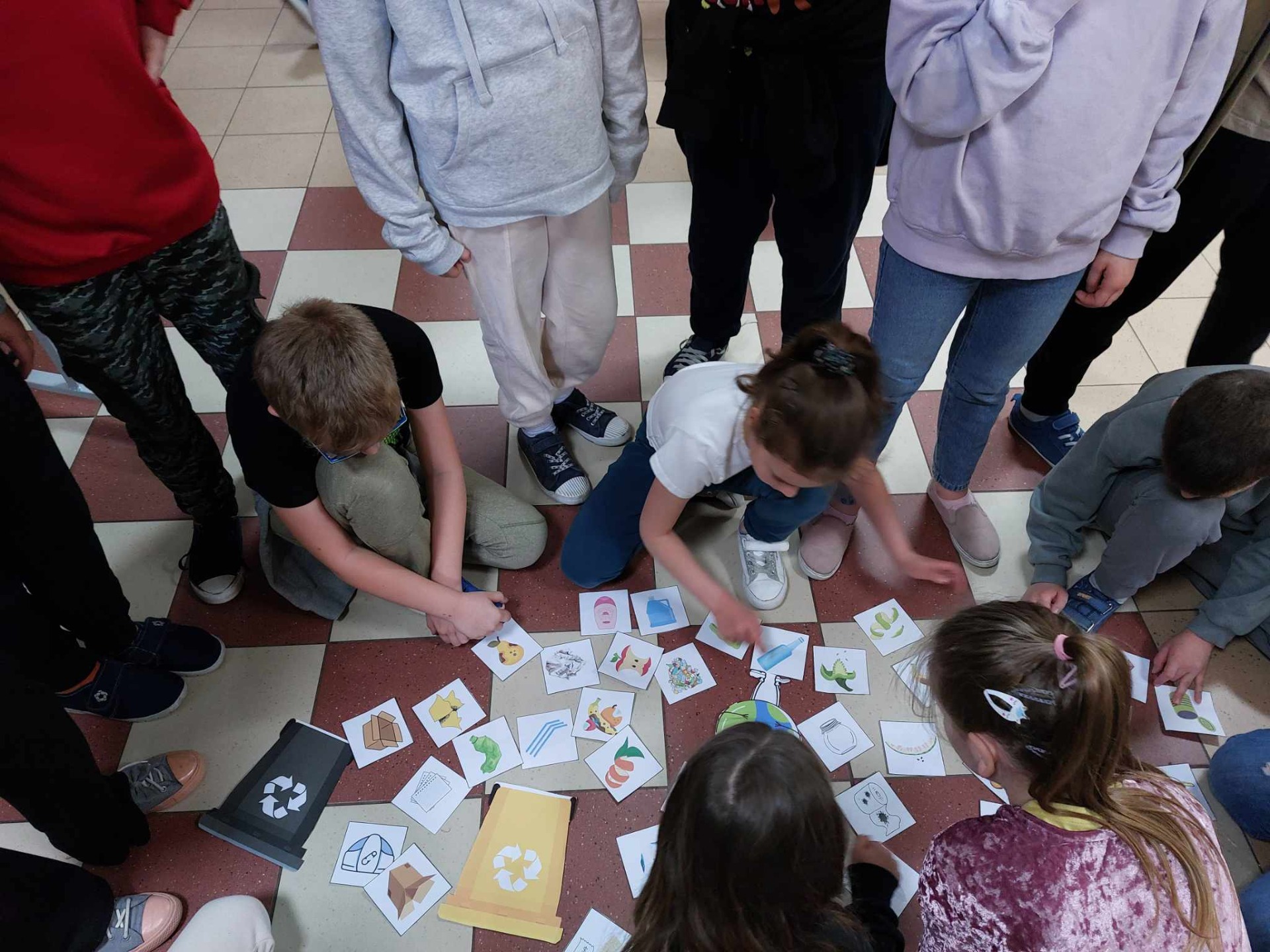 Grupa uczniów rozwiązuje quizy i zagadki o segregacji śmieci i ochronie środowiska.