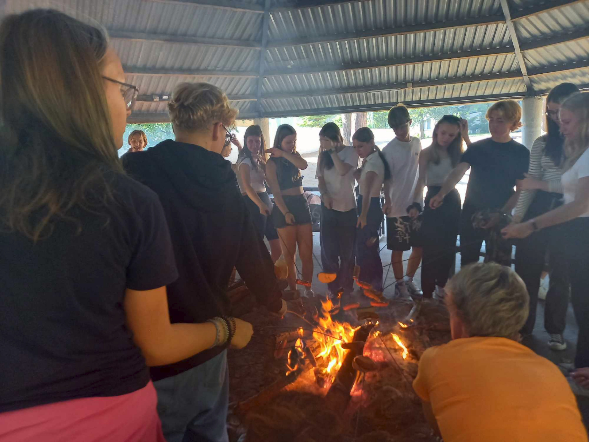uczniowie smażą kiełbaski na ognisku